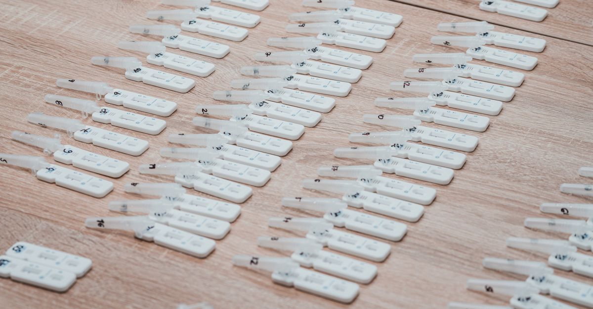 Multiple COVID-19 test kits displayed neatly on a wooden table indoors.